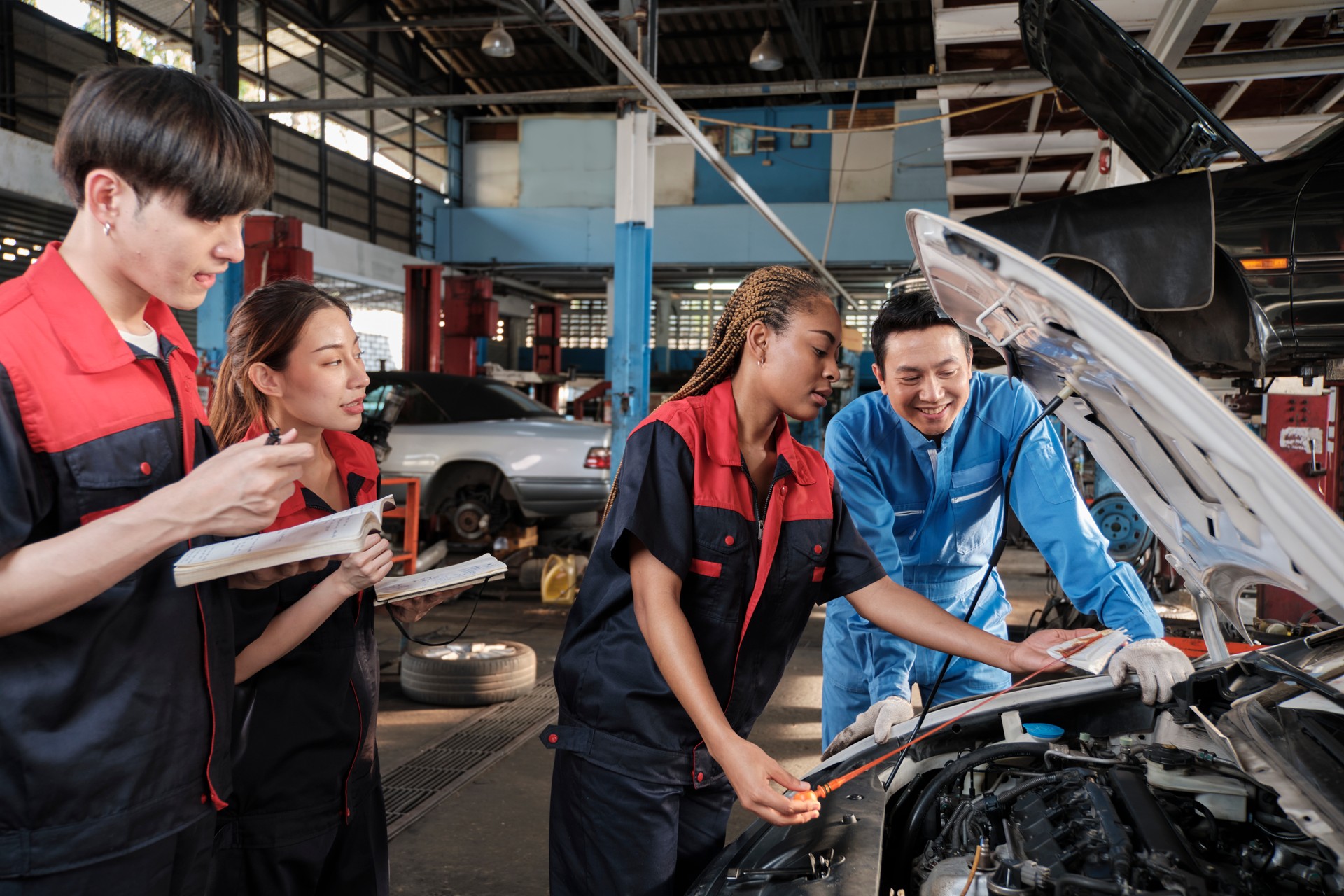 A male automotive supervisor and a Black female mechanic work in a car garage.