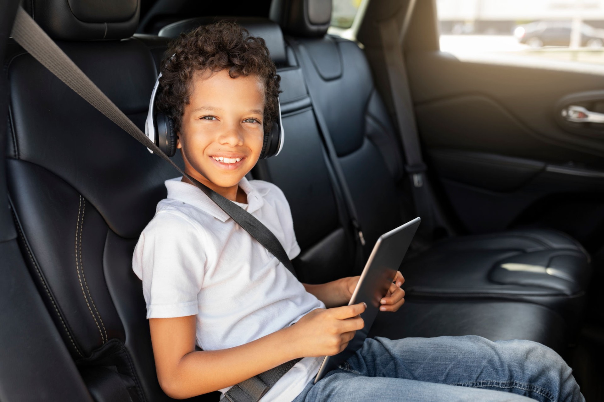 Cheerful african american boy sitting at car back seat